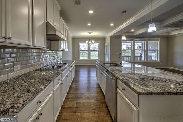 kitchen with dark wood finished floors, a center island with sink, appliances with stainless steel finishes, a sink, and under cabinet range hood