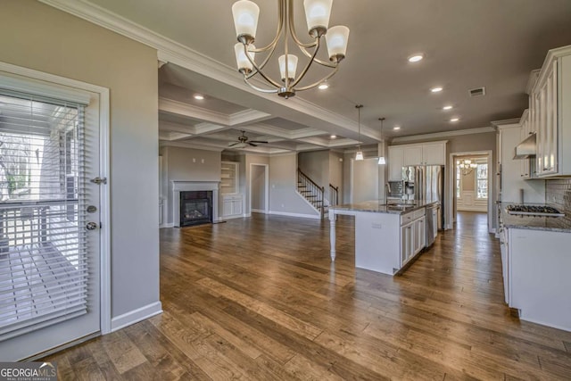 kitchen featuring a kitchen breakfast bar, dark stone countertops, decorative light fixtures, a kitchen island with sink, and white cabinetry