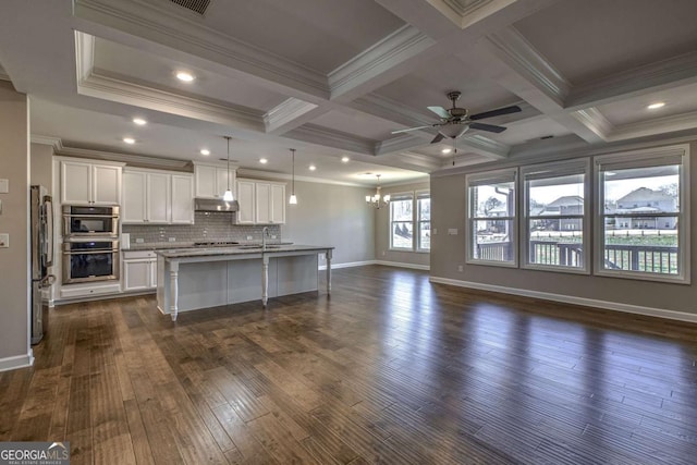 kitchen featuring white cabinets, an island with sink, appliances with stainless steel finishes, open floor plan, and decorative light fixtures