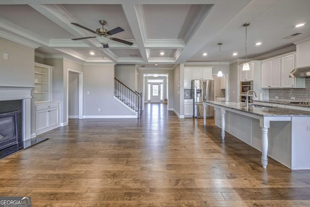 kitchen with stone counters, a sink, white cabinetry, appliances with stainless steel finishes, and decorative light fixtures