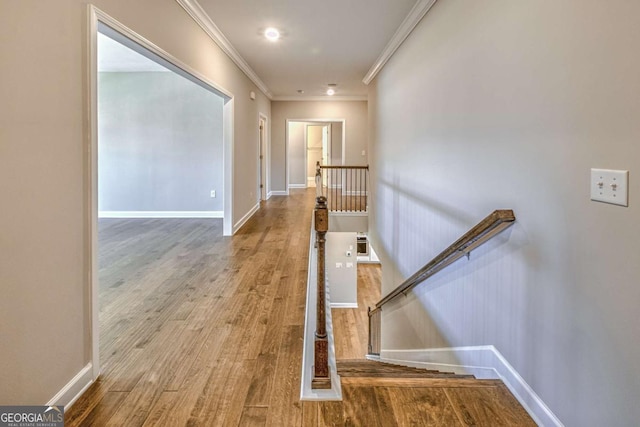 corridor with ornamental molding, baseboards, an upstairs landing, and wood finished floors