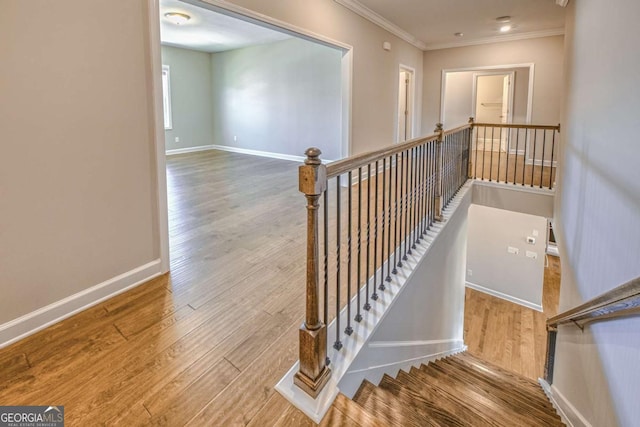 staircase with baseboards, wood finished floors, and ornamental molding