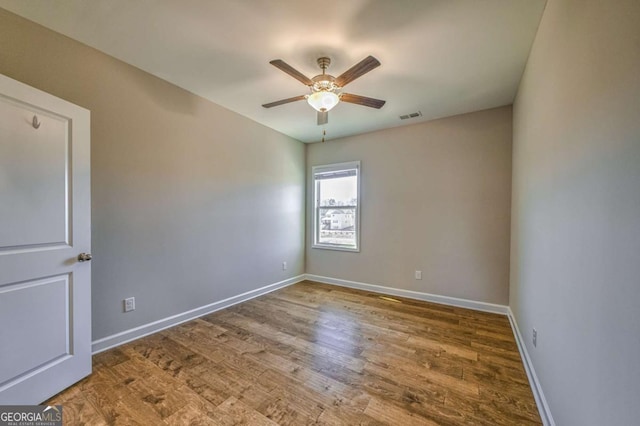 empty room with visible vents, ceiling fan, baseboards, and wood finished floors