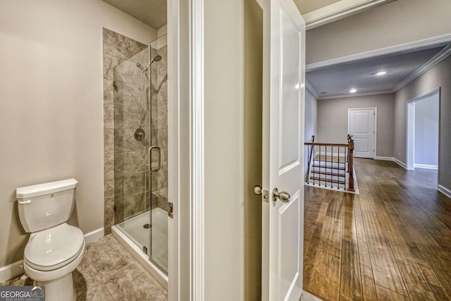 full bath with toilet, ornamental molding, a shower stall, wood finished floors, and baseboards