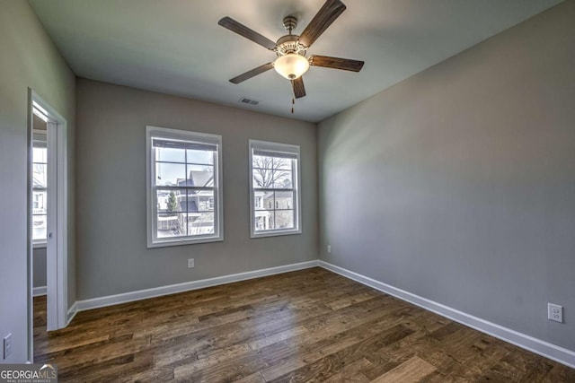 unfurnished room with dark wood-type flooring, visible vents, baseboards, and a ceiling fan