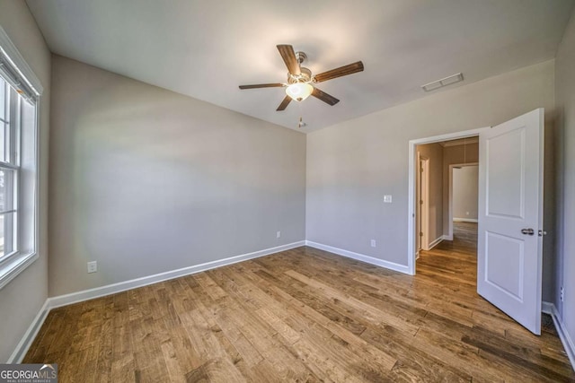 spare room with ceiling fan, wood finished floors, visible vents, and baseboards