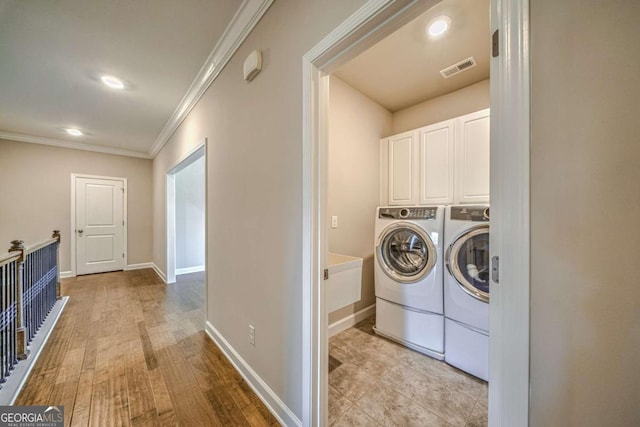 washroom with cabinet space, visible vents, baseboards, ornamental molding, and washer and dryer