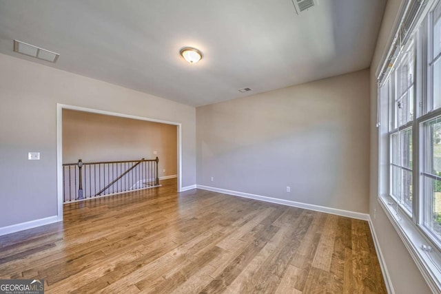 spare room featuring visible vents, plenty of natural light, and wood finished floors