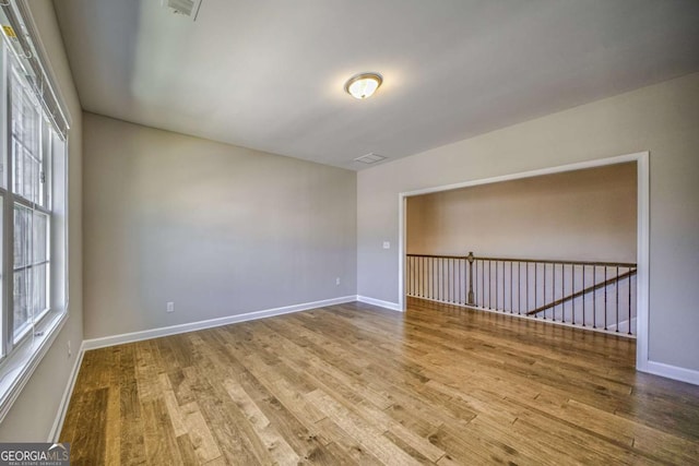 empty room with baseboards, a wealth of natural light, and wood finished floors