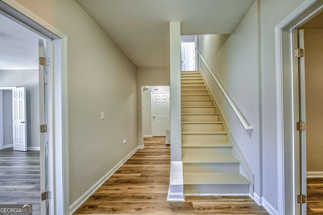 staircase featuring baseboards and wood finished floors