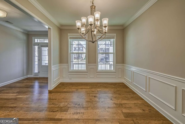 unfurnished dining area with crown molding, dark wood-type flooring, plenty of natural light, and an inviting chandelier