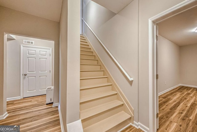 stairs with baseboards, visible vents, and wood finished floors