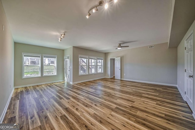 interior space featuring baseboards, dark wood finished floors, visible vents, and a healthy amount of sunlight