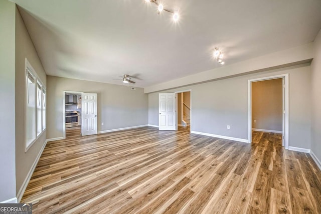 interior space with stairway, light wood-type flooring, a ceiling fan, and baseboards