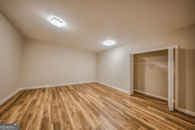 unfurnished bedroom with a closet, wood finished floors, and baseboards