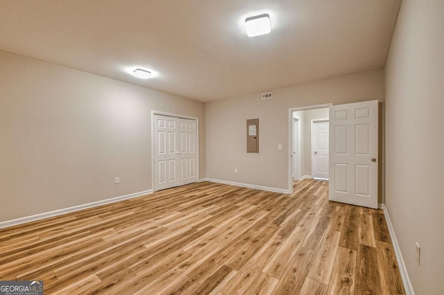 interior space with light wood-style floors, electric panel, and baseboards