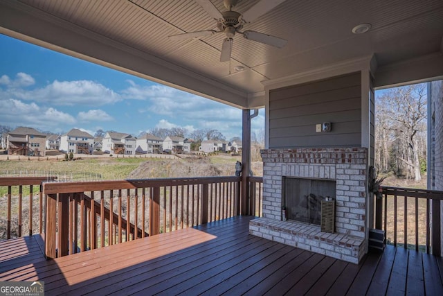 wooden terrace featuring an outdoor brick fireplace, a residential view, and a ceiling fan