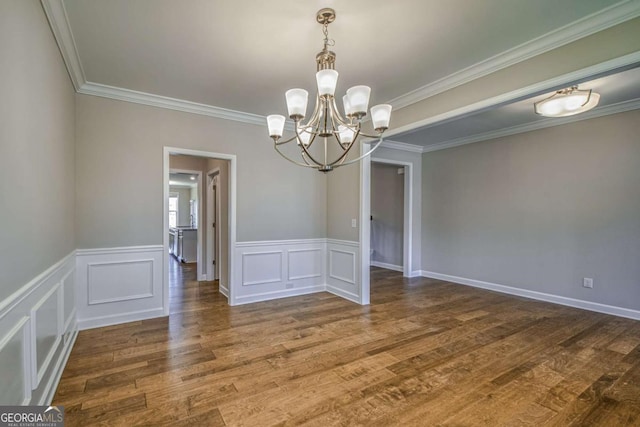 unfurnished dining area with a wainscoted wall, a decorative wall, dark wood-type flooring, ornamental molding, and a chandelier