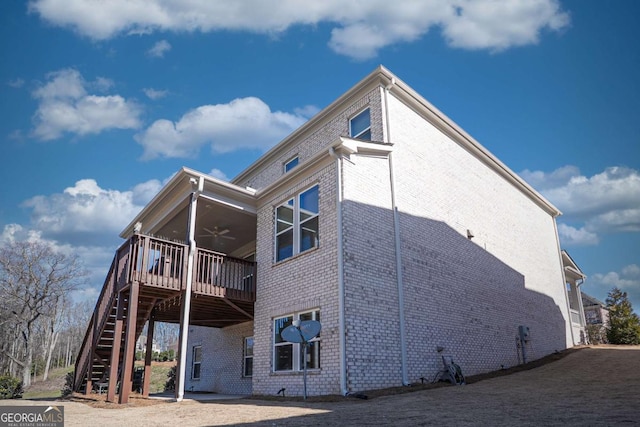 rear view of house with stairs, ceiling fan, brick siding, and a wooden deck