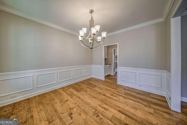 unfurnished dining area with crown molding, light wood-type flooring, and a notable chandelier