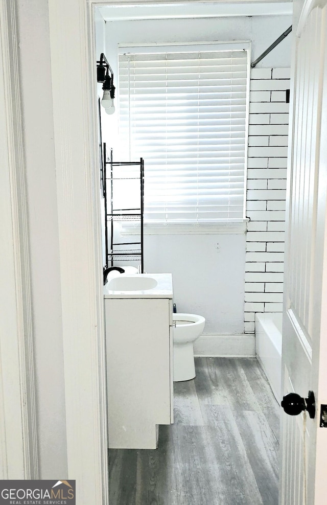 bathroom with toilet, wood finished floors, vanity, baseboards, and tub / shower combination