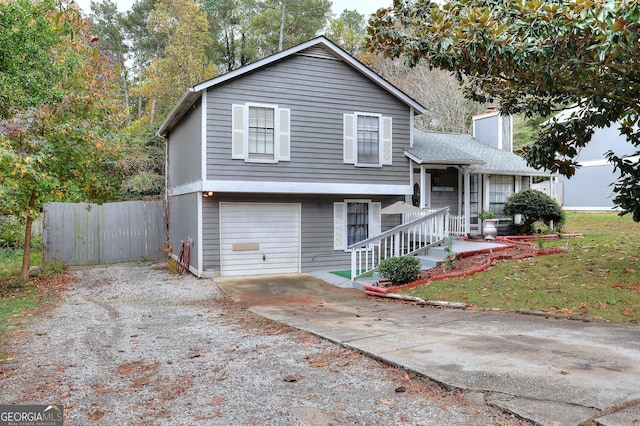 split level home featuring an attached garage, covered porch, fence, driveway, and a chimney