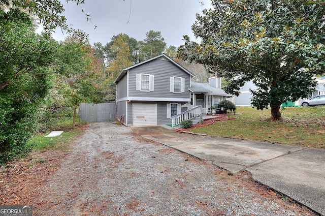 tri-level home with concrete driveway, a chimney, an attached garage, and fence