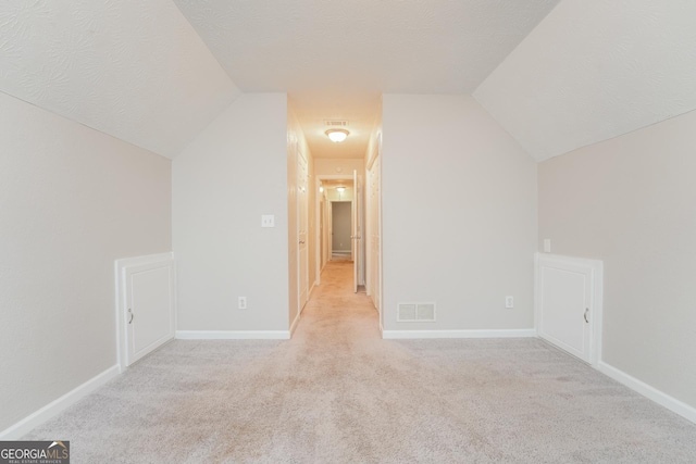 bonus room with lofted ceiling, visible vents, a textured ceiling, and light colored carpet