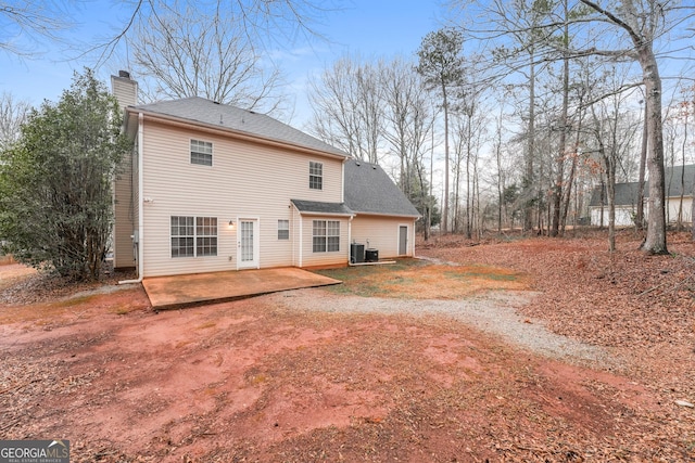 back of house featuring central air condition unit, a patio area, a shingled roof, and a chimney