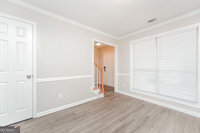 spare room featuring visible vents, light wood-style flooring, baseboards, and stairs