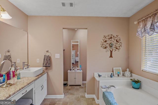 bathroom with a garden tub, baseboards, visible vents, and vanity