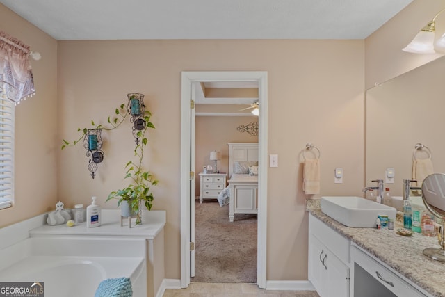 bathroom with a bathing tub, a ceiling fan, vanity, ensuite bath, and baseboards