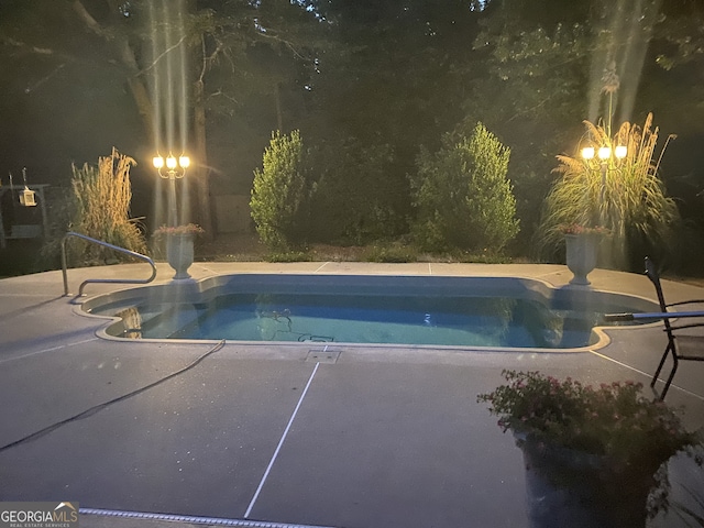 pool at night featuring an outdoor pool and a patio