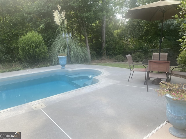 view of swimming pool featuring a patio area, fence, a fenced in pool, and outdoor dining space