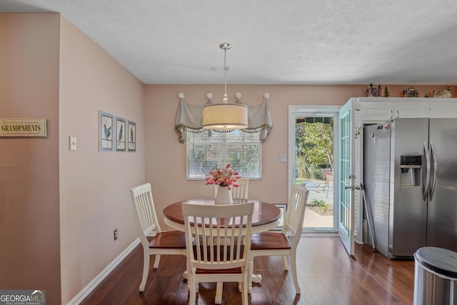 dining space featuring dark wood-style flooring, visible vents, a textured ceiling, and baseboards