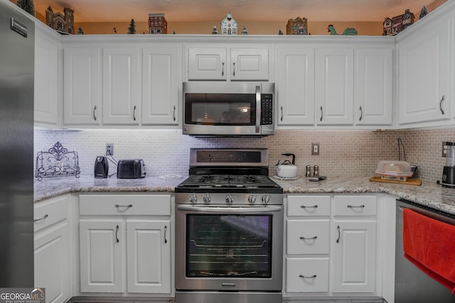 kitchen with stainless steel appliances, light stone counters, backsplash, and white cabinetry