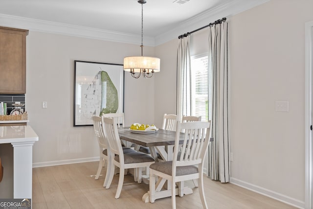 dining room with baseboards, light wood finished floors, and crown molding