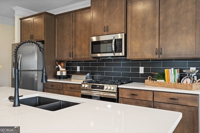 kitchen featuring backsplash, crown molding, stainless steel appliances, and light countertops