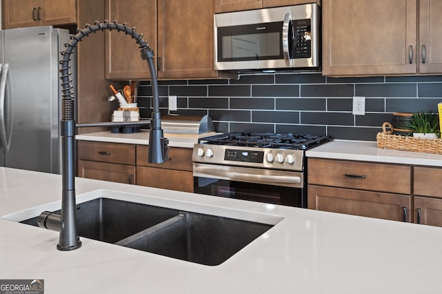 kitchen featuring appliances with stainless steel finishes, brown cabinetry, light countertops, and decorative backsplash