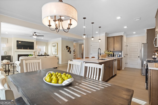 dining area with light wood-type flooring, ornamental molding, a fireplace, and recessed lighting