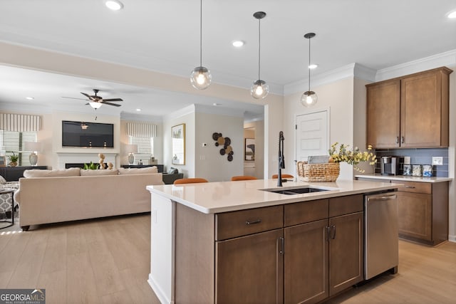 kitchen with hanging light fixtures, light wood-style floors, a kitchen island with sink, and light countertops