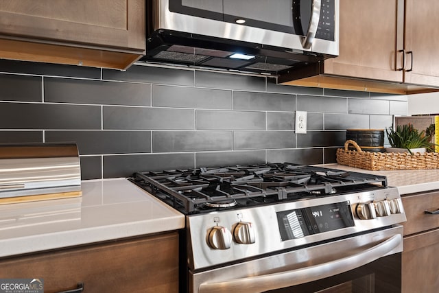 kitchen with appliances with stainless steel finishes, brown cabinets, light countertops, and tasteful backsplash