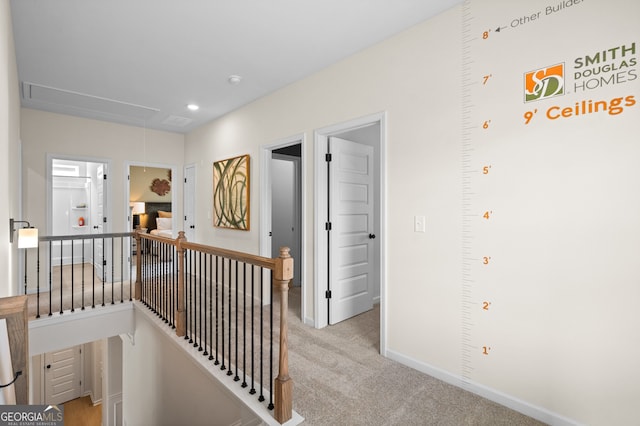 hallway with recessed lighting, light colored carpet, attic access, an upstairs landing, and baseboards