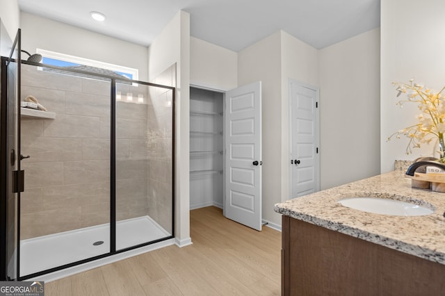 full bath with a stall shower, wood finished floors, vanity, and baseboards