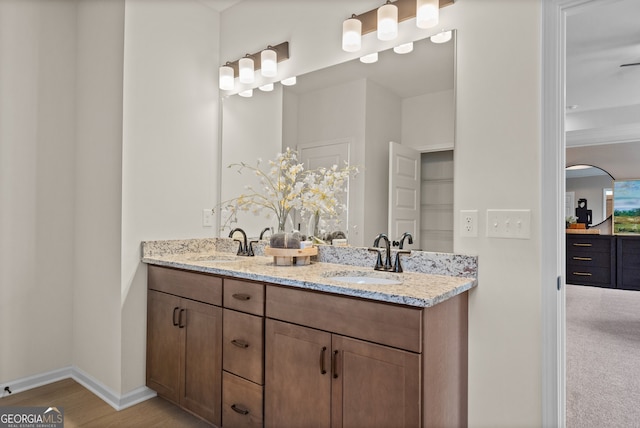 full bath with double vanity, baseboards, a sink, and wood finished floors