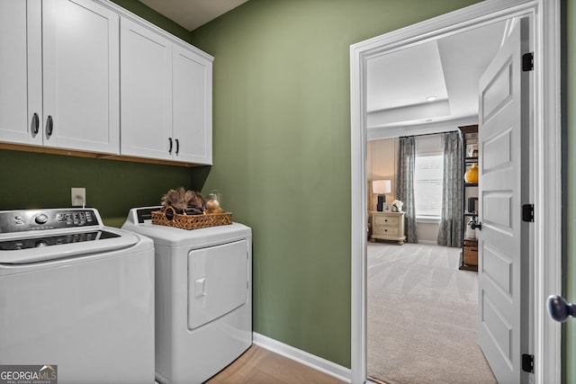 laundry room with light carpet, separate washer and dryer, cabinet space, and baseboards