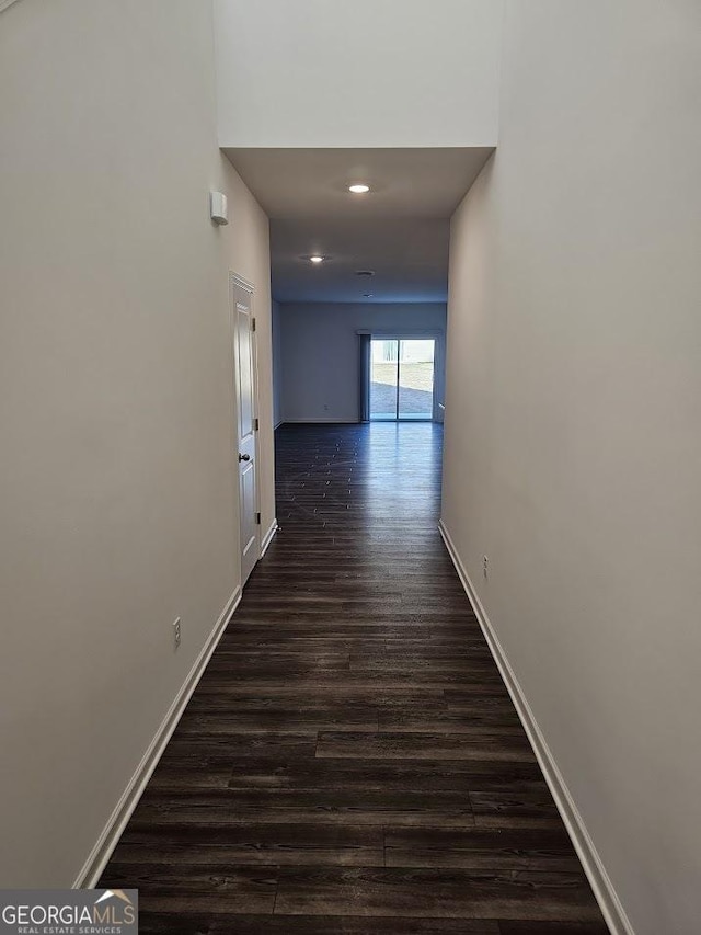 hall featuring dark wood-type flooring, recessed lighting, and baseboards