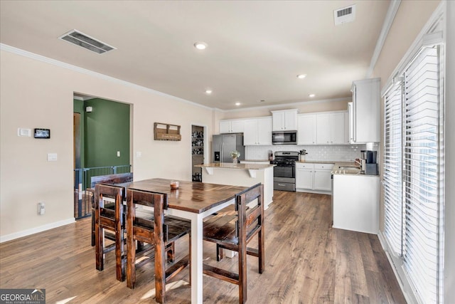 dining room featuring ornamental molding, wood finished floors, and visible vents