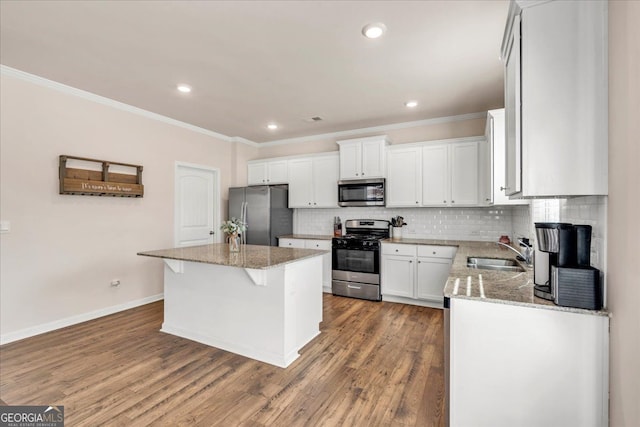 kitchen featuring a center island, stainless steel appliances, backsplash, a sink, and light stone countertops