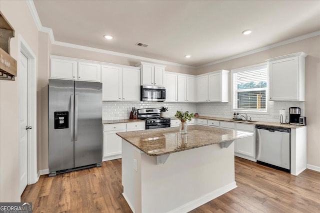 kitchen featuring appliances with stainless steel finishes, wood finished floors, and white cabinetry